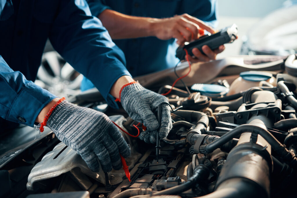 Mecânicos a diagnosticar o motor de um automóvel com multímetro